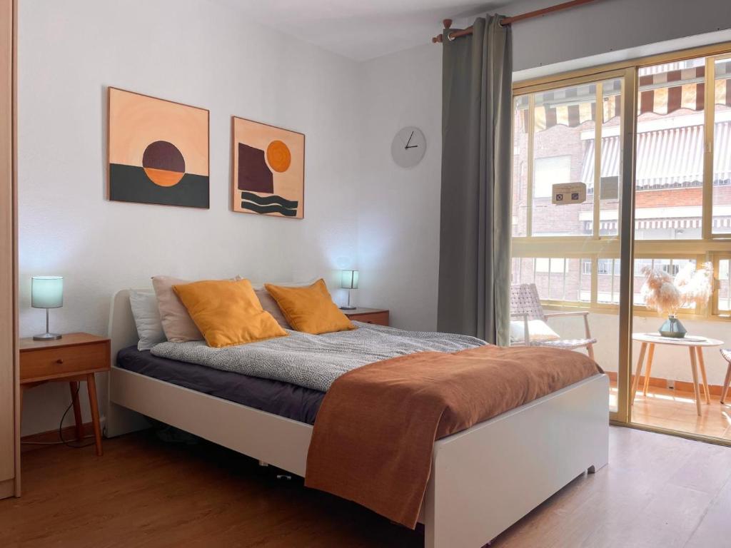 1 dormitorio con 1 cama con almohadas de color naranja y ventana en Estudio Marina de Santa Pola, en Santa Pola