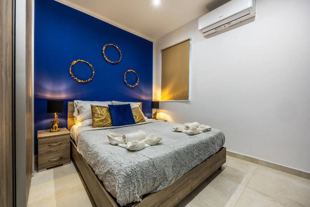 een slaapkamer met een kingsize bed en een blauwe muur bij Dorris's Apartment 5 min walk from St Julians in San Ġwann