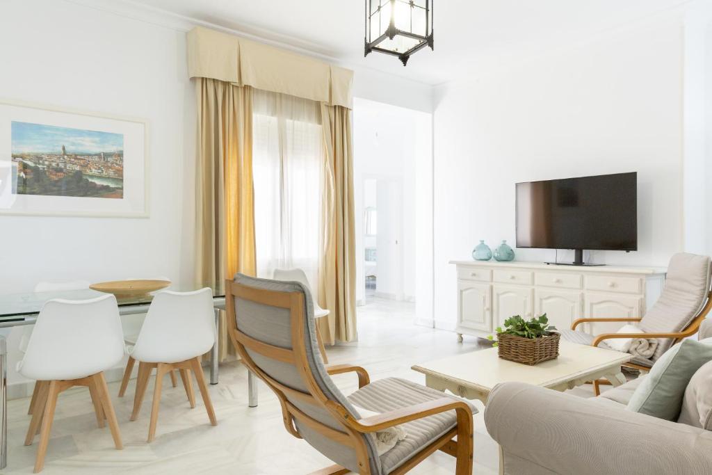 a living room with white furniture and a tv at Luminoso y amplio piso en Chipiona 5 in Chipiona