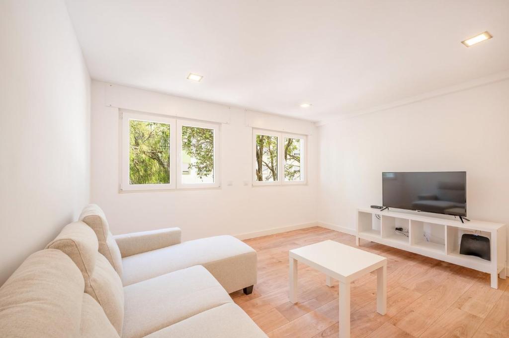 sala de estar blanca con sofá y TV en GuestReady - Arcos Residence near the beaches, en Paço de Arcos