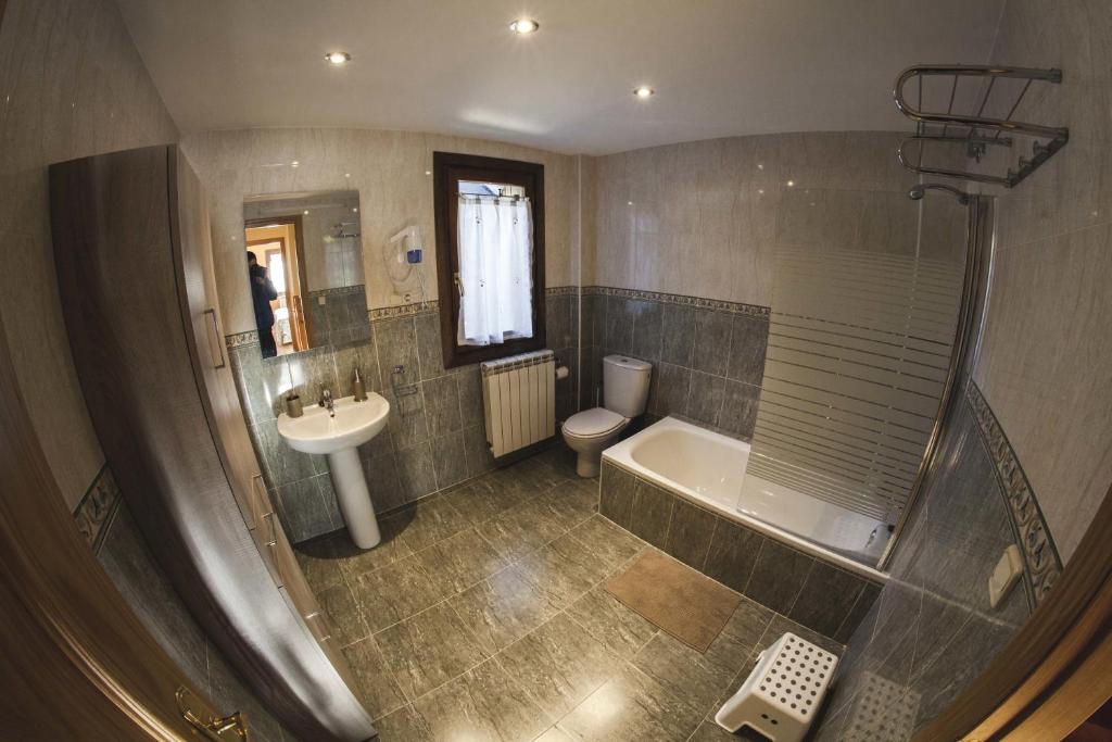 een badkamer met een bad, een toilet en een wastafel bij Rincón de bachatos in Piedrafita de Jaca