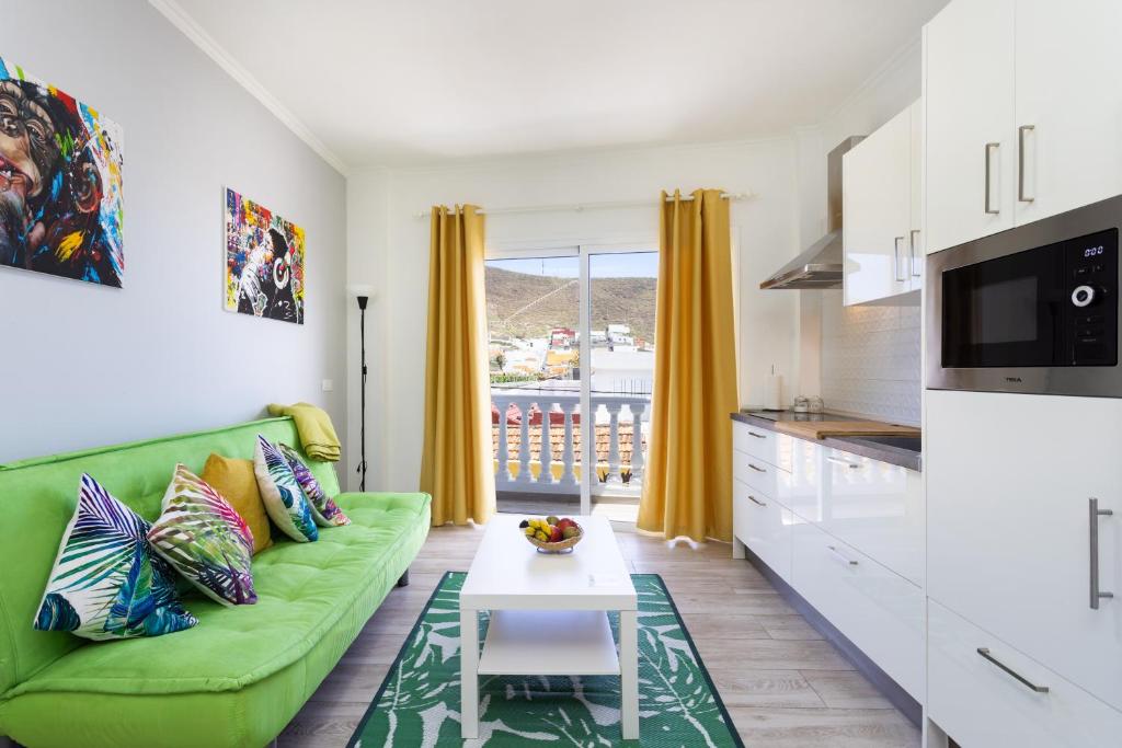 Una sala de estar con un sofá verde y una mesa. en Home2Book Charming Apt Mountain Views Los Silos, en Los Silos