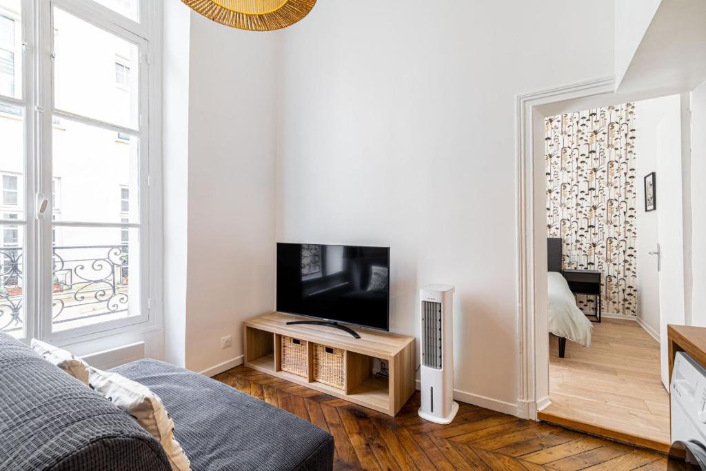 un salon avec une télévision à écran plat et un canapé dans l'établissement GuestReady - Bel Appartement Le Marais, à Paris
