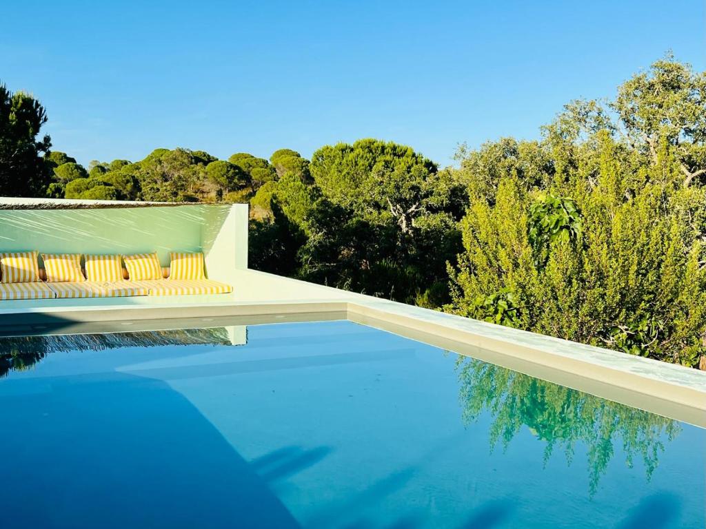 a swimming pool with a bench and some trees at Cabanas de Melides in Melides