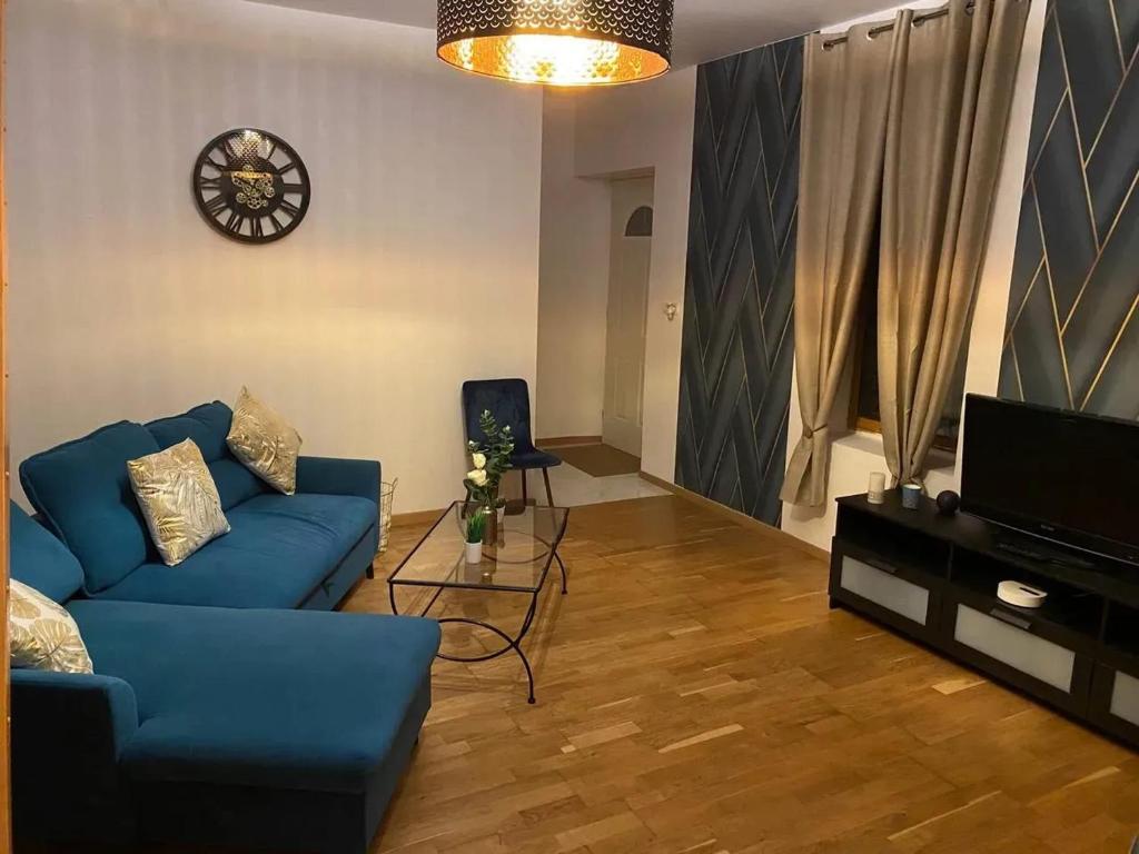 a living room with a blue couch and a television at Charmante maison à Troyes avec terrasse et jardin clôturé in Troyes