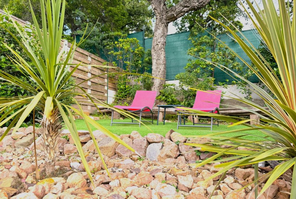 2 chaises roses et une table dans un jardin dans l'établissement R1D Les Pléiades de l'Estérel - Agay, à Agay