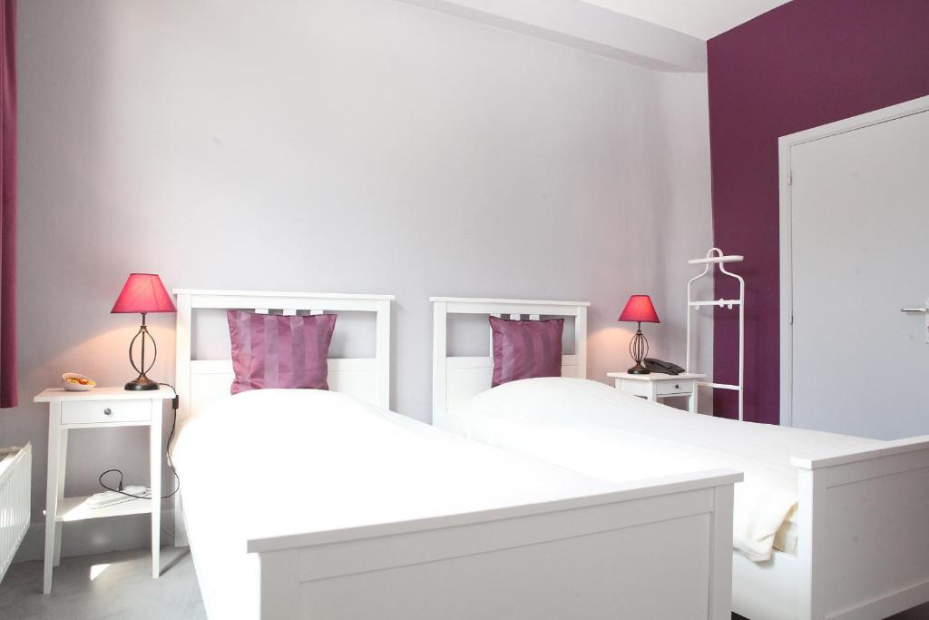 a bedroom with two white beds and purple walls at Eurotel in Liège