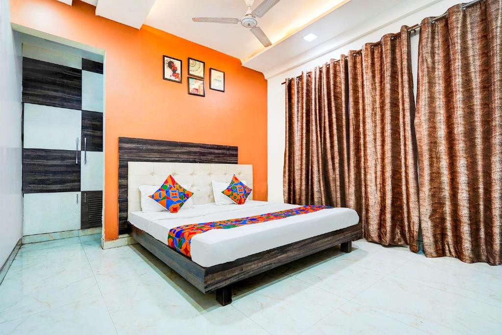 a bedroom with a bed with orange walls and curtains at FabHotel Season Grand in New Delhi
