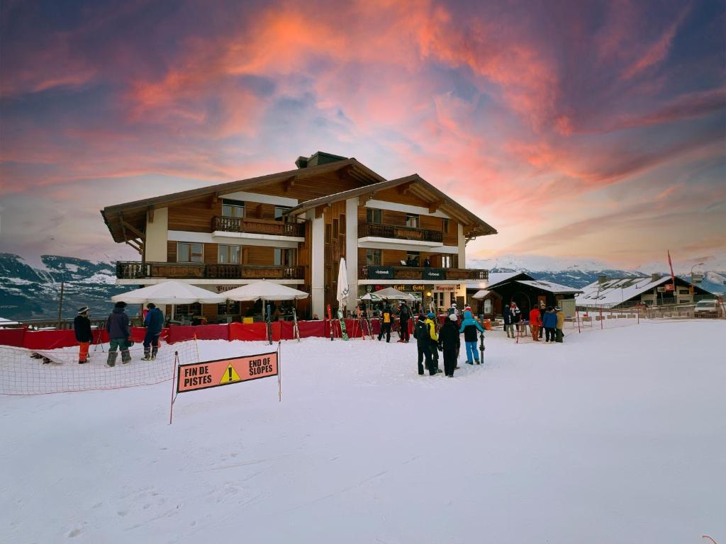 a group of people standing in the snow in front of a lodge at Hôtel Magrappé in Veysonnaz