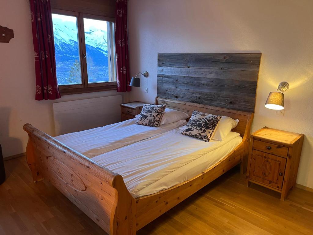 a bedroom with a wooden bed with two pillows on it at Hôtel Magrappé in Veysonnaz