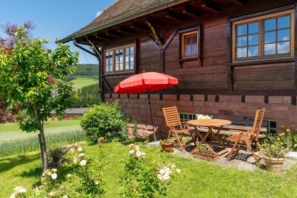 une maison en bois avec une table, des chaises et un parasol dans l'établissement Ferienhaus Charlotte, à Zell am Harmersbach
