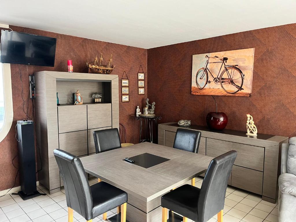 een eetkamer met een tafel en een fiets aan de muur bij Camping De Collignon in Cherbourg en Cotentin