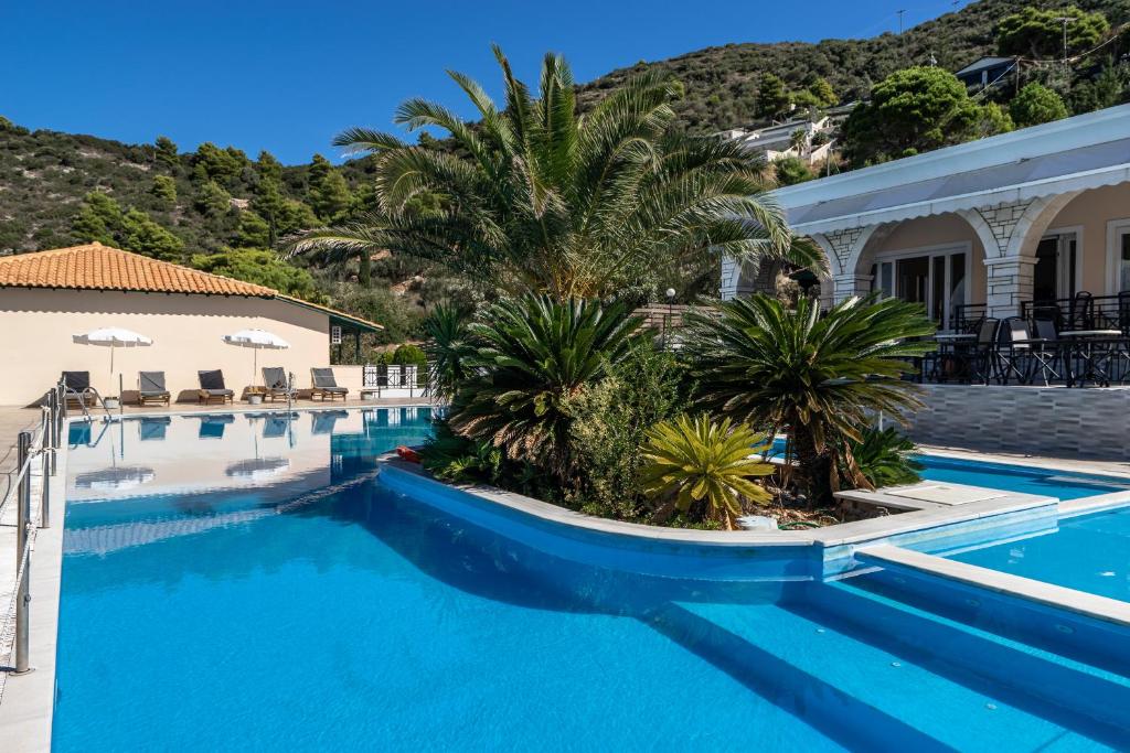 Una piscina con palmeras al lado de un edificio. en Sunset Triple 2, en Agios Nikitas