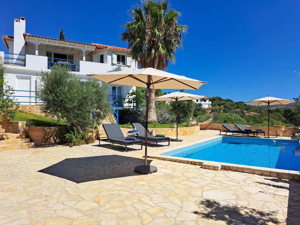 a pool with two chairs and an umbrella next to a building at Villa Emilios in Lakhanádha