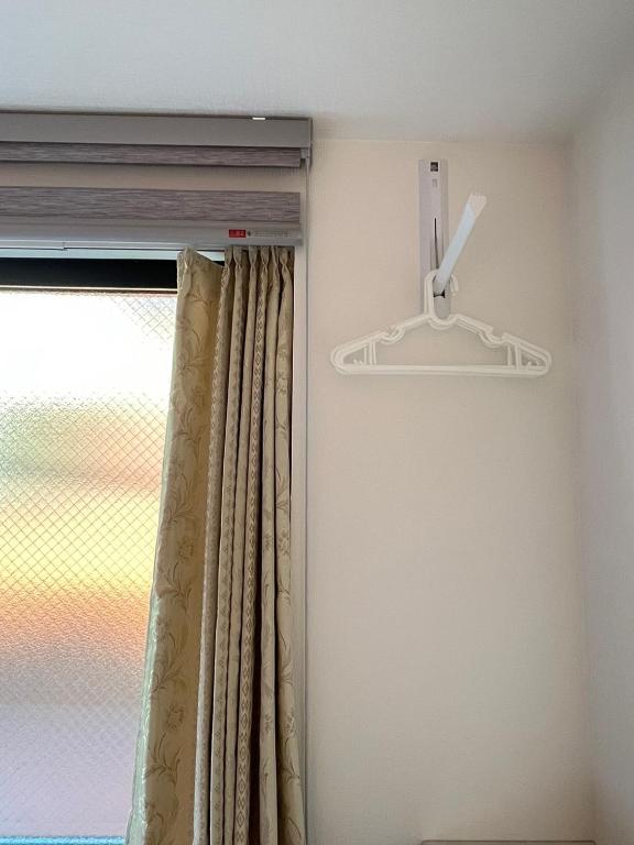 a window with a curtain and a hanger at DainHostel2 in Tokyo