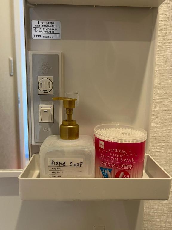 a shelf with a hand sanitizer and a container in a bathroom at DainHostel2 in Tokyo