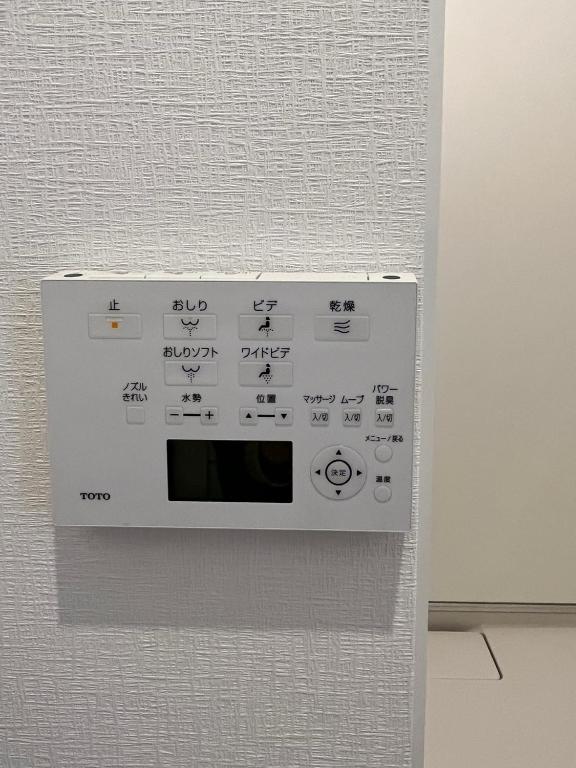 a white microwave with writing on the side of a wall at DainHostel2 in Tokyo