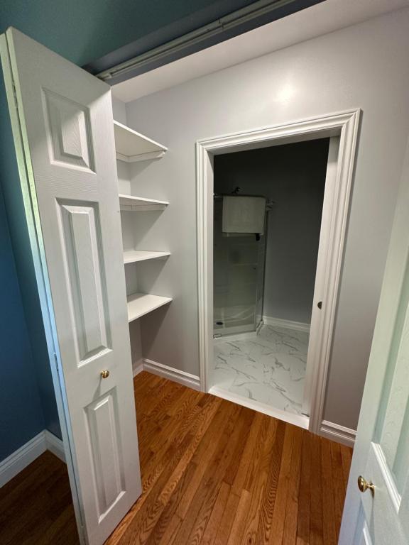 a closet with white shelves and a door at Eden Estate B&B in Reidville