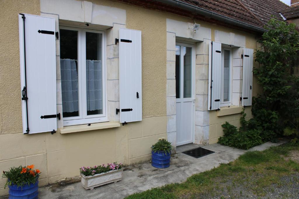 une maison avec des volets blancs et des fleurs dessus dans l'établissement LA MAISON DE GILYDIE, à Chabris