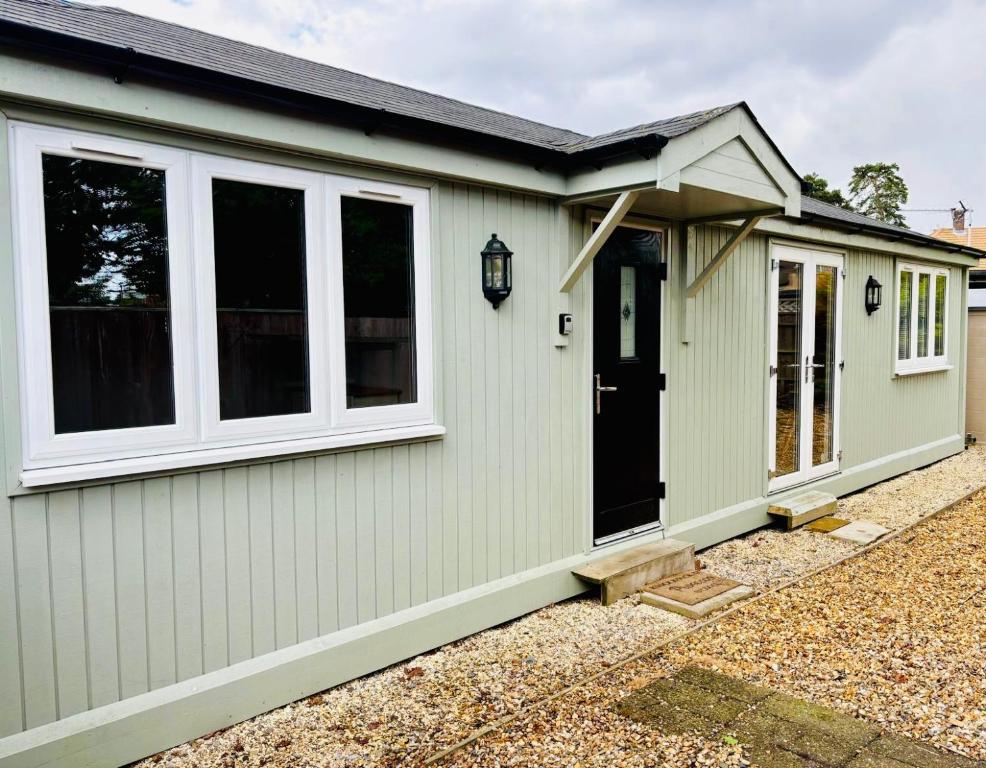 Hampshire lodge في كامبرلي: منزل أخضر مع باب أسود ونوافذ