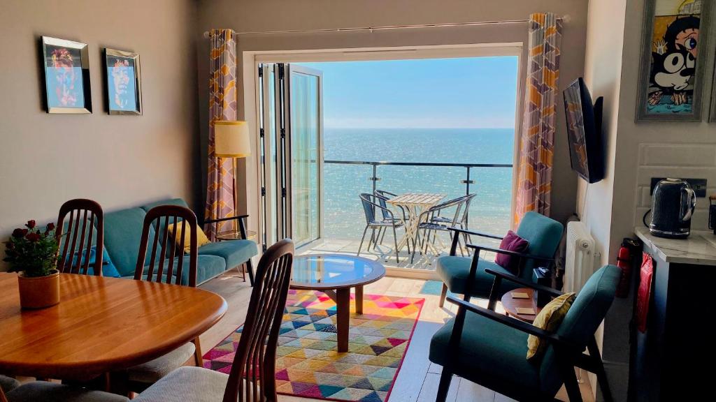 Sala de estar con mesa y vistas al océano en Seascape - 2 bedroom flat with panoramic sea views en Hollington