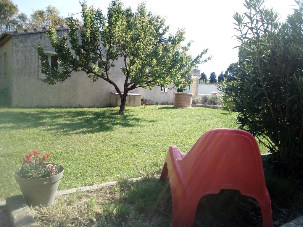 une chaise rouge dans une cour avec un arbre dans l'établissement Maison RomanEva, à Pélissanne