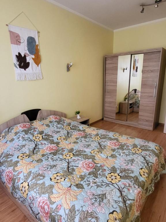 1 dormitorio con cama con colcha de flores en Giedres apartaments-Alkava, en Kaunas
