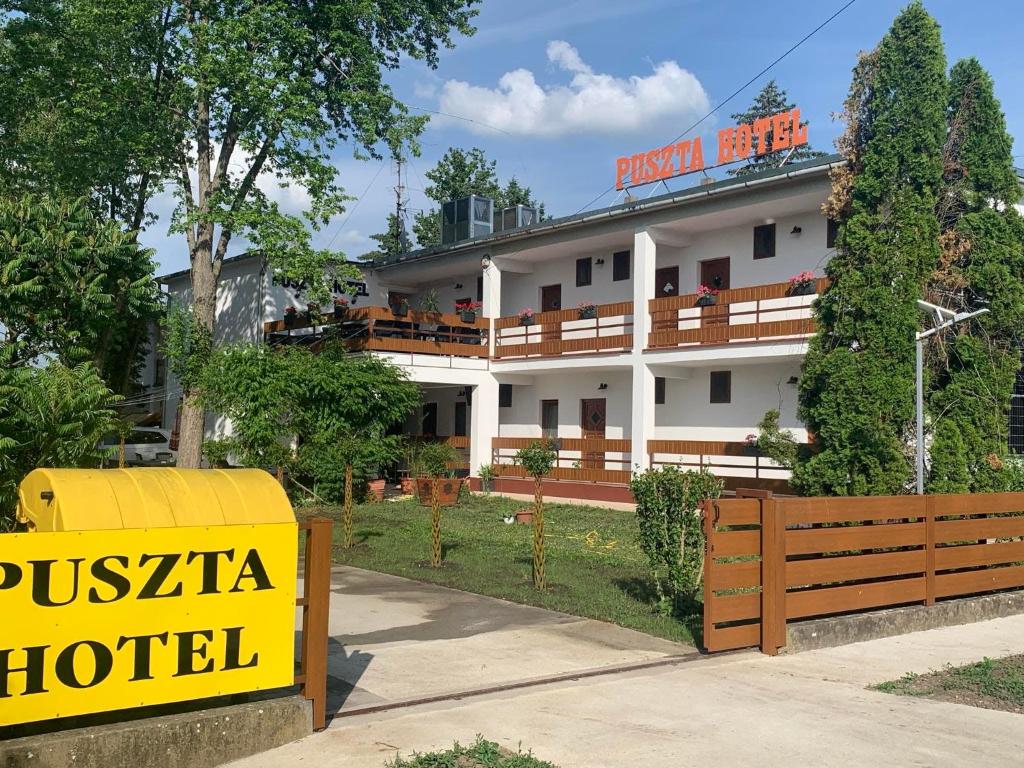 a hotel with a yellow sign in front of a building at Puszta Hotel in Berekfürdő
