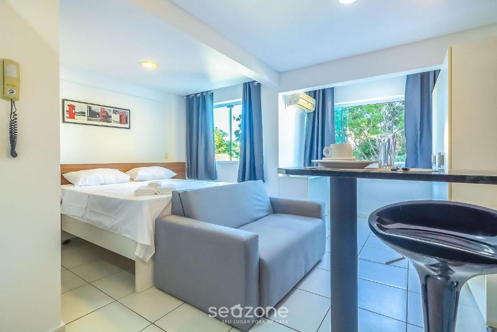 a bedroom with a bed and a chair and a table at SPT - Studios Convenientes em Blumenau/SC in Blumenau