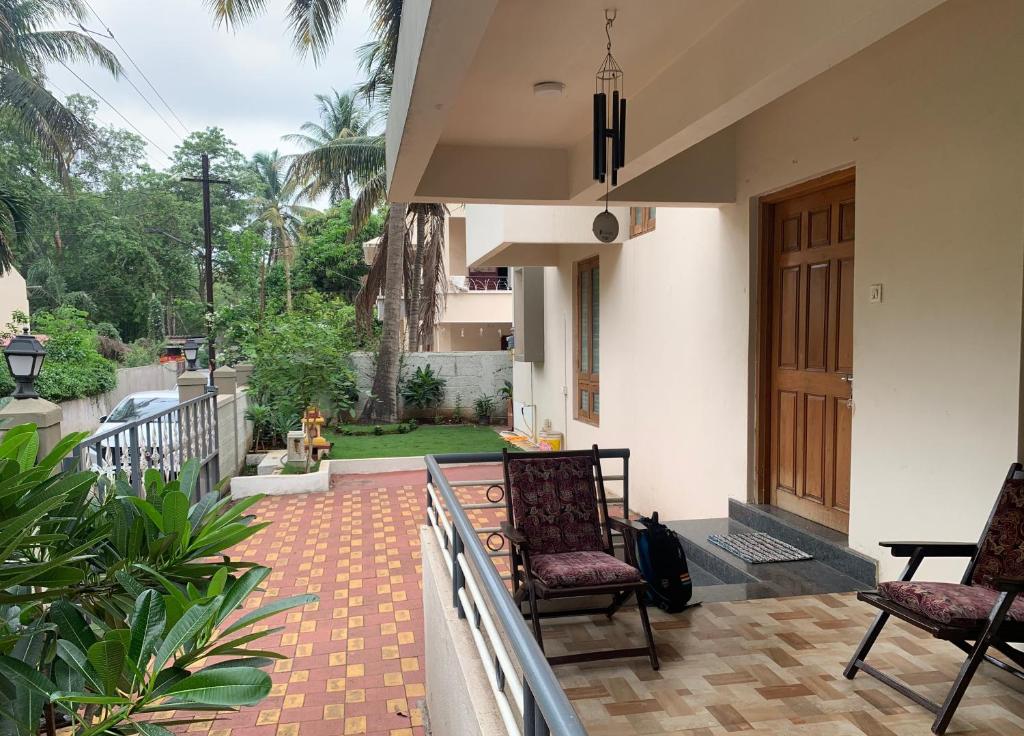 a porch with two chairs and a wooden door at Home Away From Home in Kolhapur