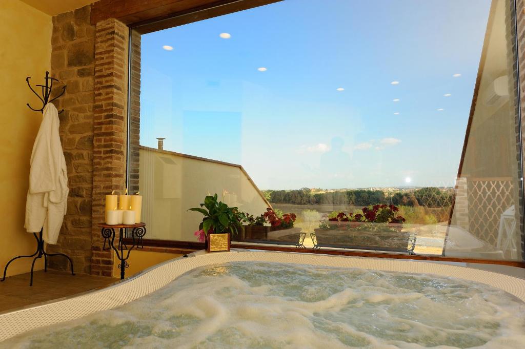 a bath tub in a room with a large window at Borgo Mandoleto - Country Resort & Spa in Solomeo