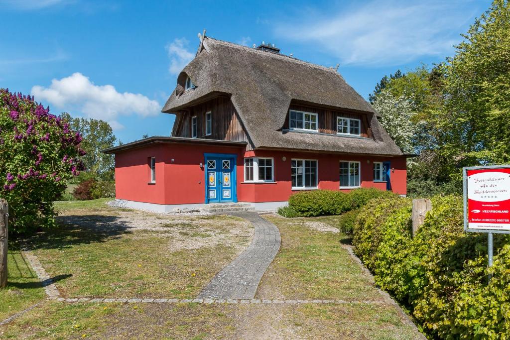 a red house with a thatched roof and a driveway at An den Boddenwiesen 02 in Wieck