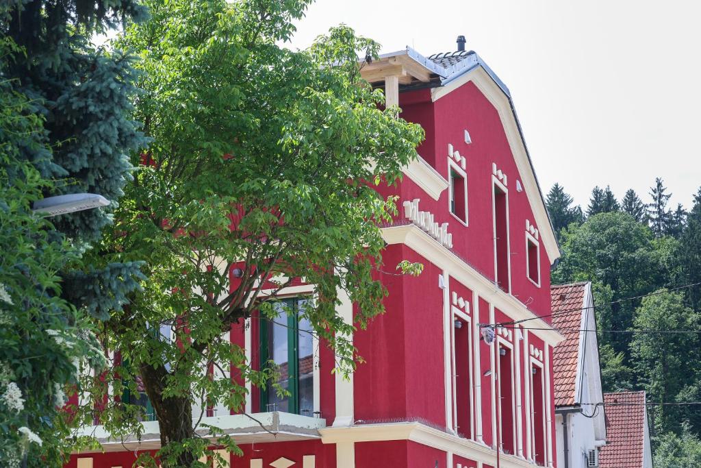 un edificio rojo con un árbol delante de él en APART HOTEL ASTERIA, en Liubliana