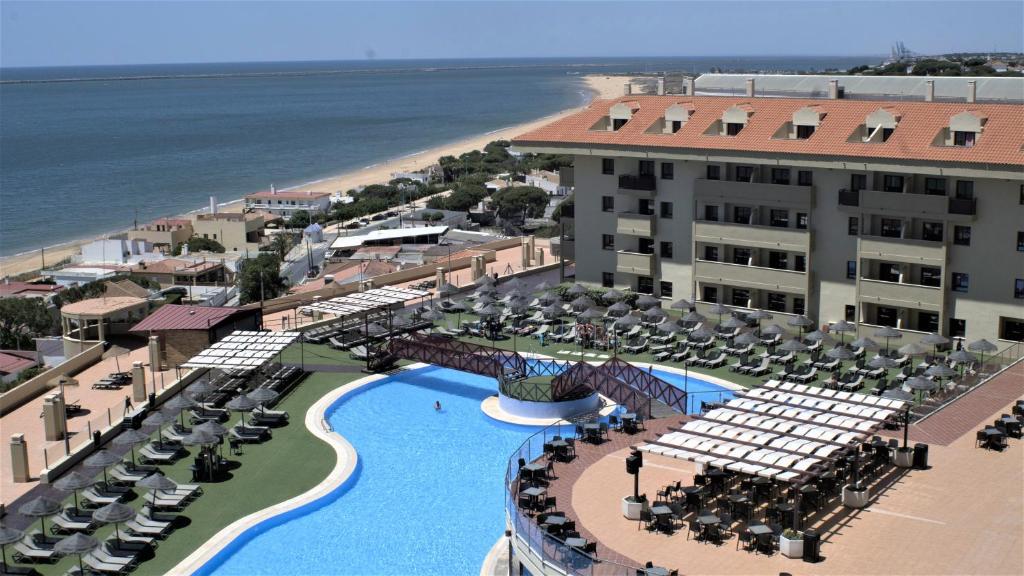 uma vista aérea de um resort com uma piscina e uma praia em Ohtels Mazagon em Mazagón