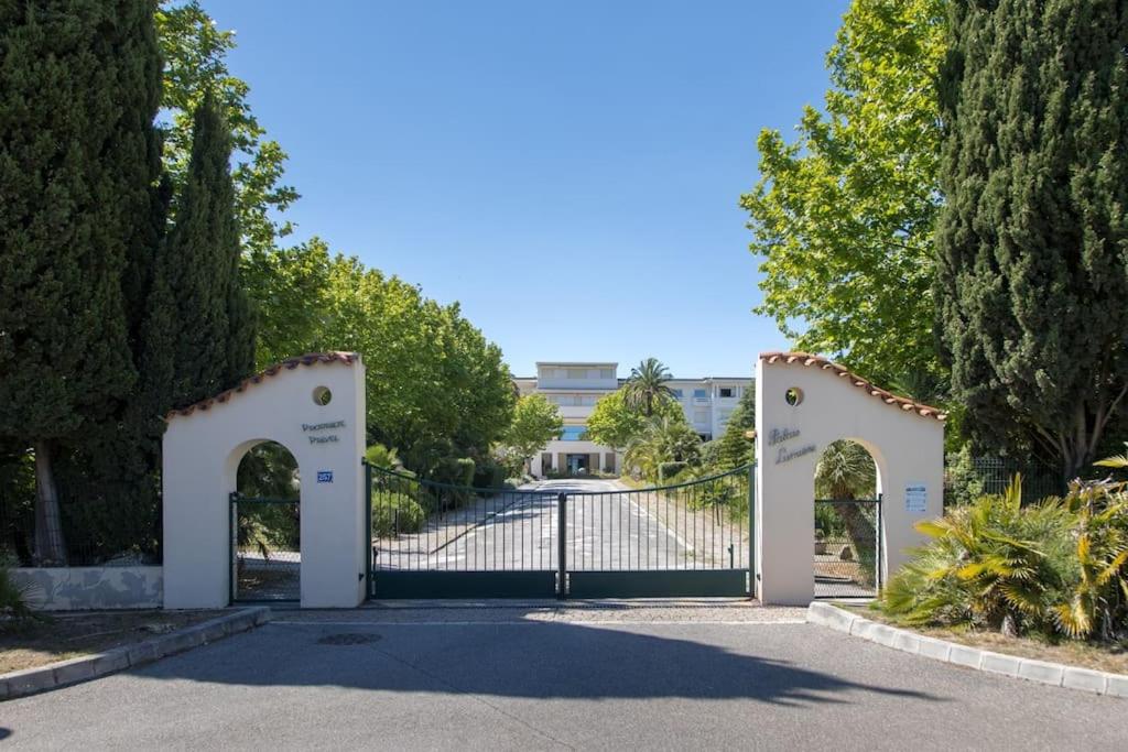 une porte menant à une allée avec un bâtiment en arrière-plan dans l'établissement Charmant studio avec vue mer à La Ciotat, à La Ciotat