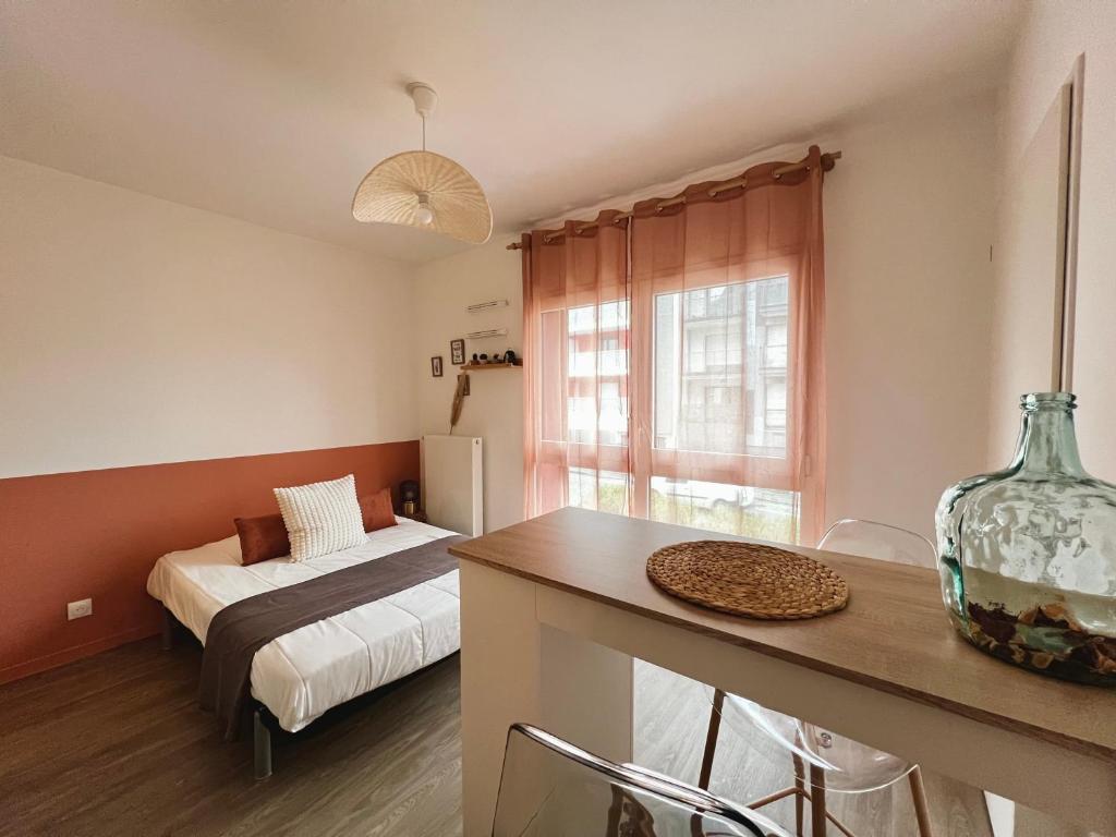 - un salon avec un lit et une table avec un vase dans l'établissement Le Vitré, Rennes Est, à Rennes