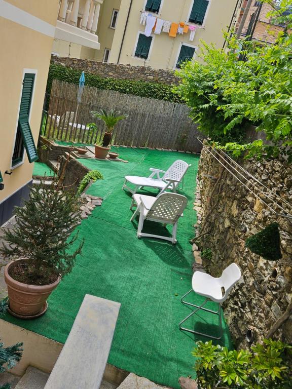 a backyard with a green rug and chairs and a fence at Affittacamere House LeoMar di Sara in Genoa