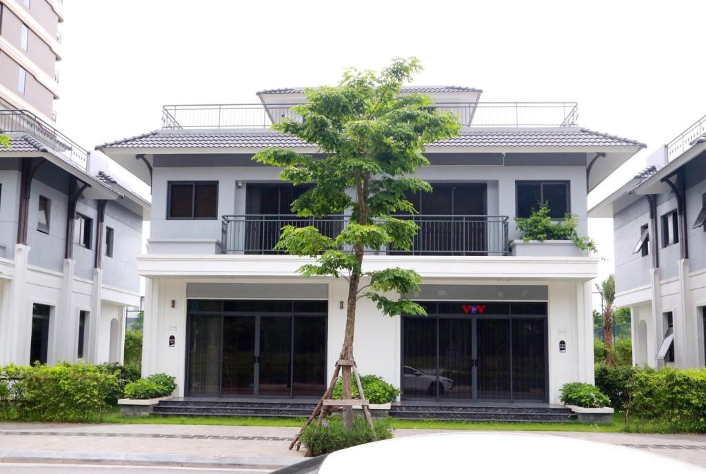 un árbol frente a un edificio blanco en Green Bay Luxury Villa Sonasea Vân Đồn 