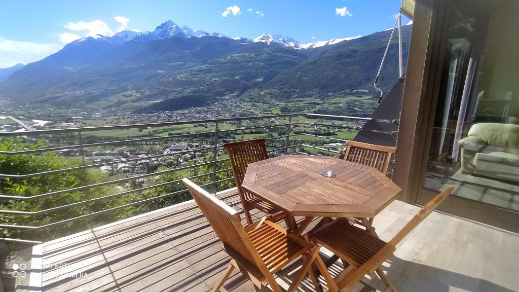 un tavolo in legno con sedie e un balcone con vista sulle montagne. di Atmosfera e vista mozzafiato Chalets ad Aosta