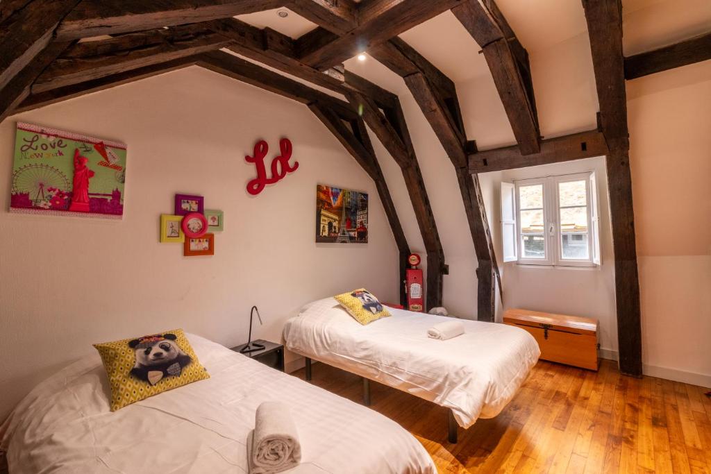 サルラ・ラ・カネダにあるLes Chambres du "Coup de Coeur de Sarlat"のベッド2台と窓が備わる客室です。