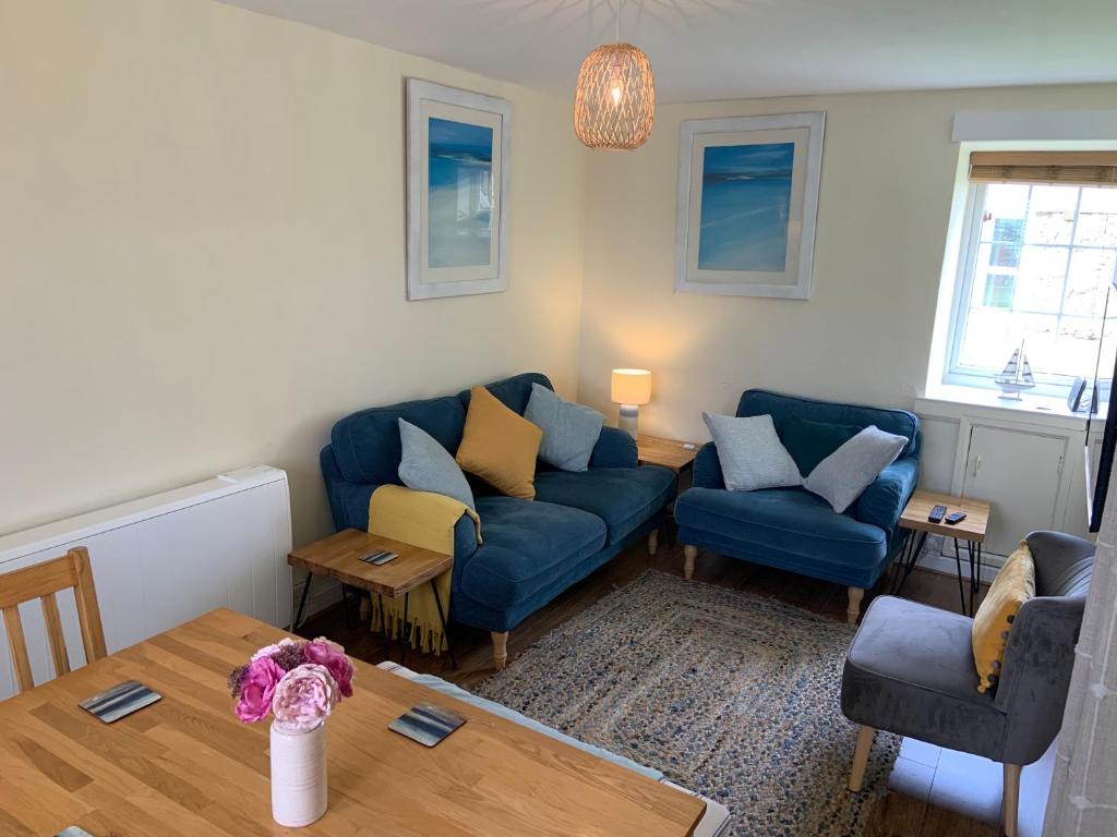 ein Wohnzimmer mit 2 blauen Sofas und einem Tisch in der Unterkunft Large 3 bedroom flat in Sennen in Penzance
