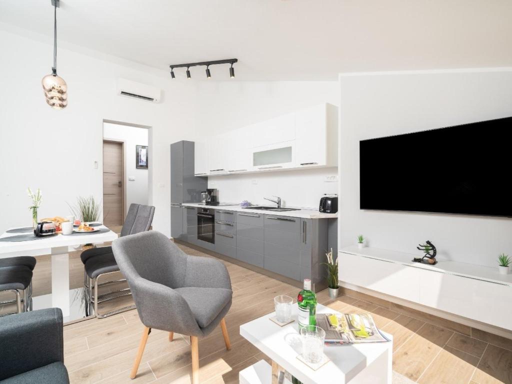 een witte woonkamer met een tv en een keuken bij Apartment Gaia in Labin