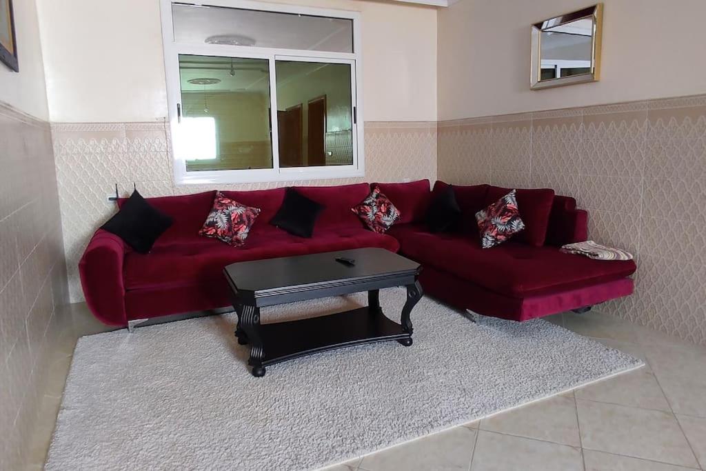 a red couch in a living room with a table at Logement familial 3 in Selouane
