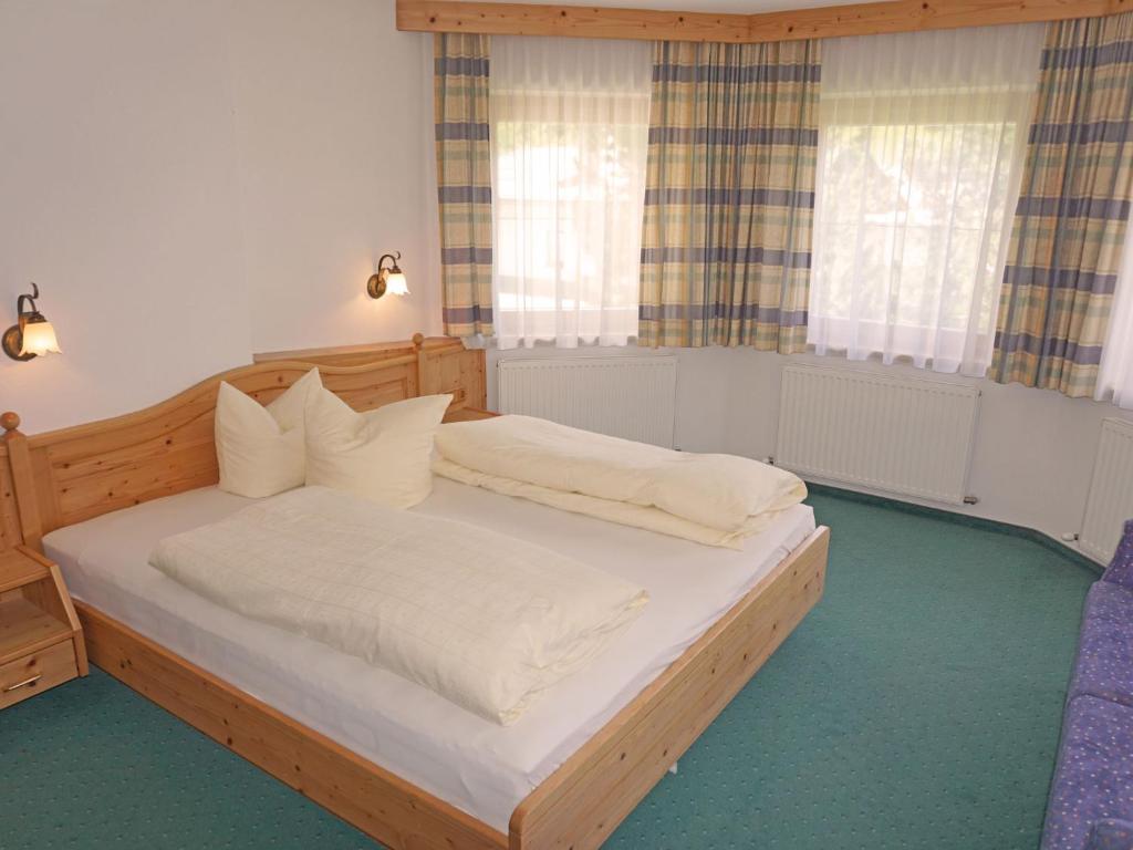 sypialnia z drewnianym łóżkiem i 2 oknami w obiekcie Apartment Diana-3 by Interhome w mieście Pettneu am Arlberg