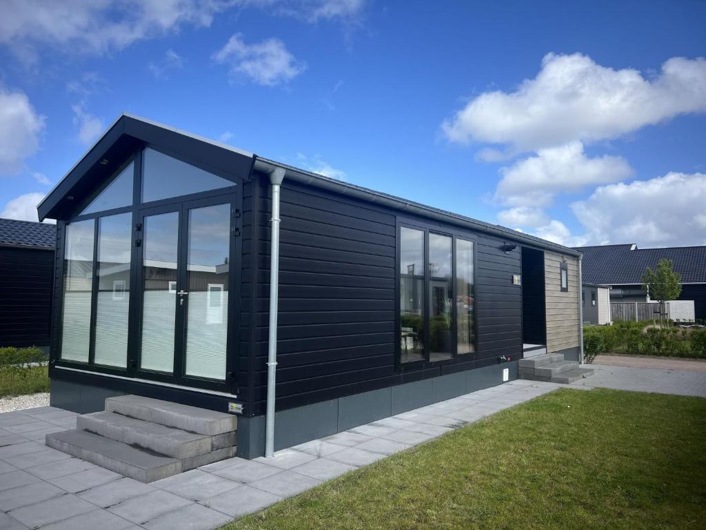 a black house with glass windows and a lawn at Holiday Home De Zeeparel by Interhome in Scherpenisse