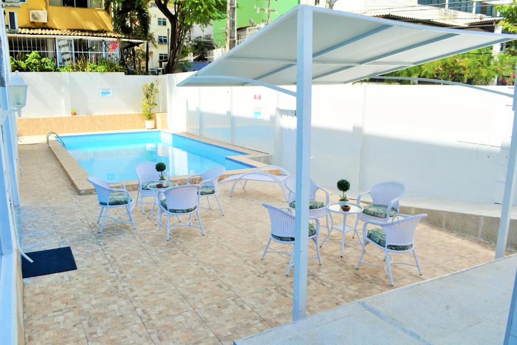 un patio con mesa, sillas y piscina en Hotel Americas, en Fortaleza