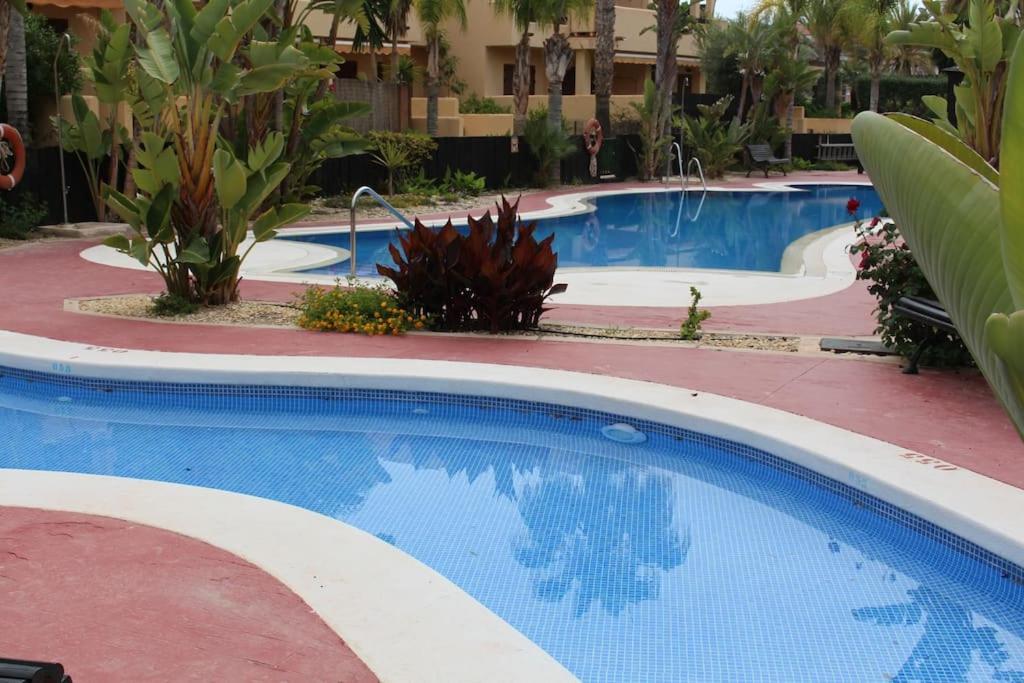 two pools in a resort with palm trees and plants at Espectacular casa Playas de Vera in Playas de Vera