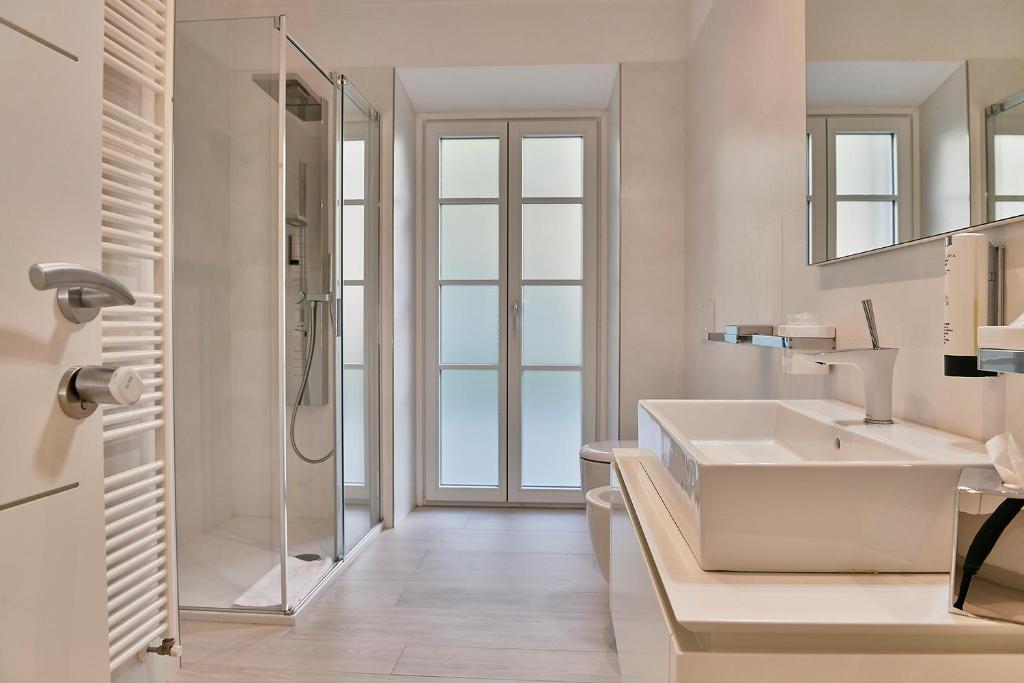 a white bathroom with a sink and a shower at Wosching Haus Roemer Living in Merano