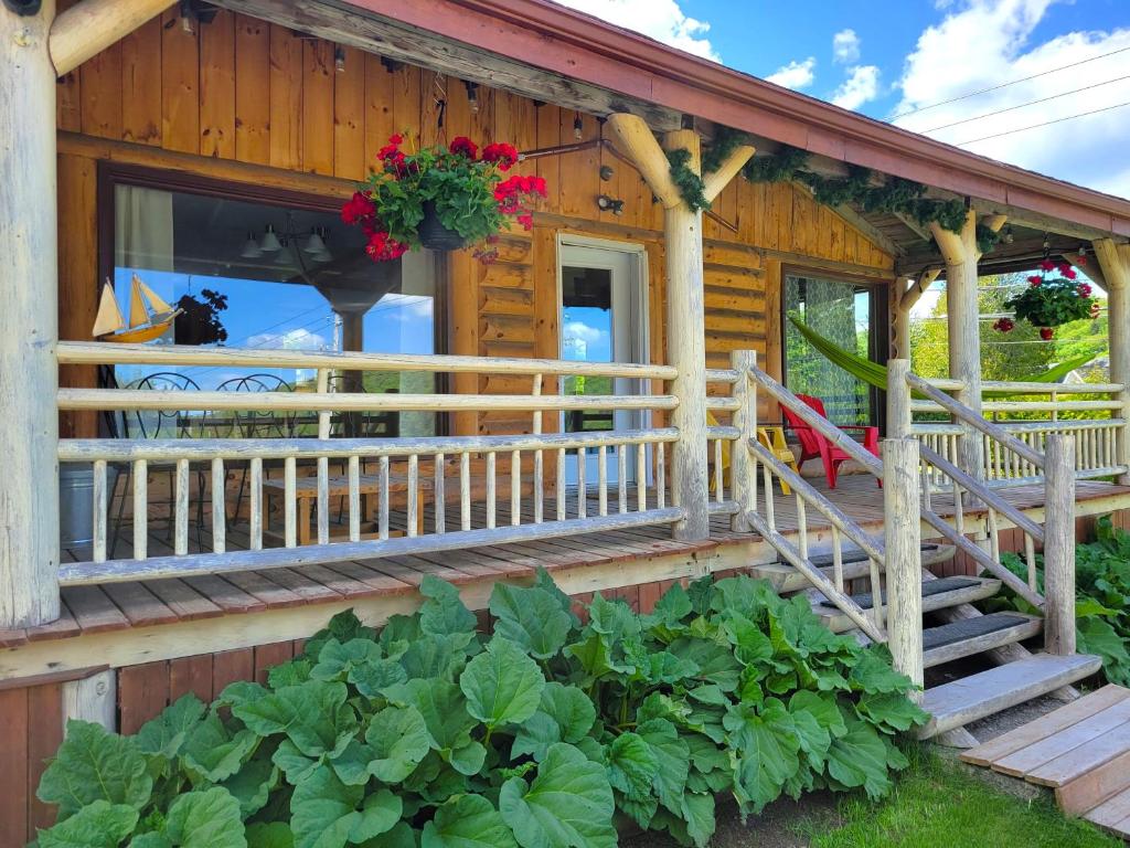 a wooden house with a porch and a balcony with flowers at Retraite au lac avec SPA privé et embarcations in Saint Adolphe D'Howard