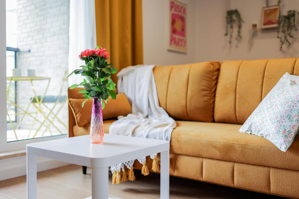 uma sala de estar com um sofá e uma mesa com um vaso de flores em Glow Apartments, Apartamenty Nowa Letnica em Gdansk